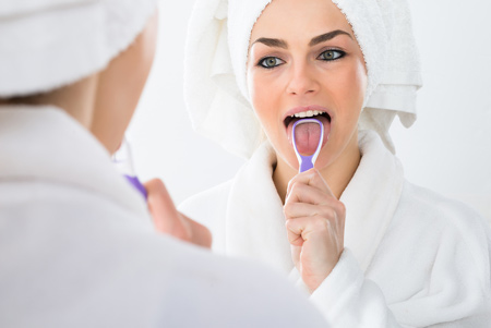 Woman using tongue scraper